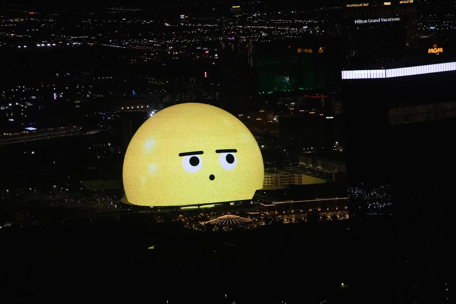 The Sphere lit as a giant face above the Las Vegas skyline at night